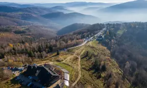Widok z lotu ptaka na górski krajobraz jesienią. Widać hotel, parking, drogę i szlak równica z dzieckiem.
