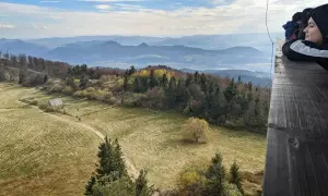 Widok z wieży widokowej na **Lubań szczyt**. Jesienne barwy lasów i pól, w oddali pasmo górskie.