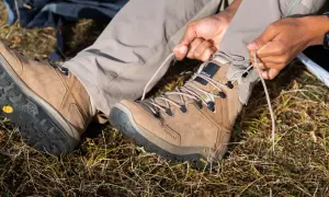 Przygotowanie do wędrówki. Osoba sznuruje brązowe buty trekkingowe z podeszwą Vibram XS Trek, gotowa na przygodę.