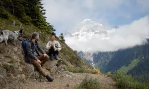 Para, pies i pies odpoczywają na szlaku. To jest właśnie trekking – odkrywanie górskich krajobrazów.