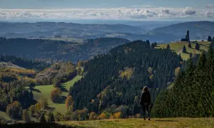 Widok na jesienne wzgórza z dalimilova rozhledna w oddali. Kobieta podziwia krajobraz.