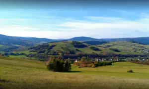Malowniczy krajobraz z zielonymi wzgórzami i lasami, gdzieś w tle majaczy góra Grzywacka.