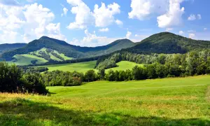 Zielone wzgórza i lasy Beskidu Niskiego pod błękitnym niebem z chmurami. Widok na malownicze szczyty.