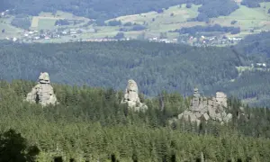 Skaliste formacje, znane jako Pielgrzymy, górują nad lasem w Karkonoszach. W oddali widać zabudowania Karpacza.