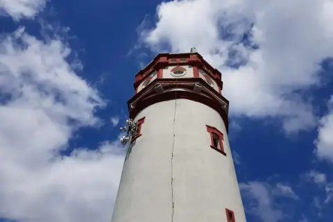 Wieża widokowa na Biskupiej Kopie z czerwonymi akcentami i antenami, na tle błękitnego nieba z chmurami.