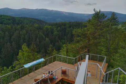 Drewniany punkt widokowy w Karpaczu z widokiem na Karkonosze. Dwie kobiety odpoczywają na tarasie.
