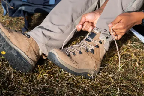 Przygotowanie do wędrówki. Osoba sznuruje brązowe buty trekkingowe z podeszwą Vibram XS Trek, gotowa na przygodę.