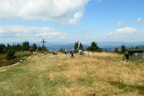 Wielka racza szlaki to widok na szczyt z krzyżem i ludźmi odpoczywającymi na trawie.