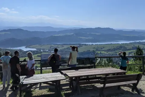 Widok z góry Wdżar na jezioro i góry. Grupa turystów podziwia panoramę.