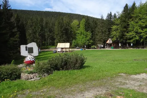 Przełęcz Krowiarki, z pomnikiem i chatkami, otoczona lasem.