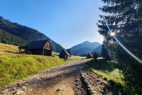 Kamienne schroniska pasterskie w dolinie, z widokiem na grześ szczyt. Słoneczny poranek w górach.
