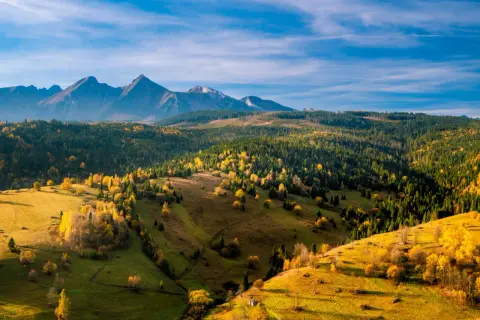 Jesienne słońce oświetla wzgórza i lasy, tworząc malowniczy krajobraz. Idealne tatry słowackie szlaki dla średnio zaawansowanych.