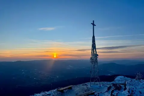 Zachód słońca nad Bieszczadami. Krzyż na szczycie, zimowy krajobraz i ławki czekające na turystów. Smerek w tle.