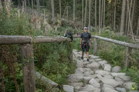 Kamienista ścieżka prowadzi przez las, a turyści idą w kierunku wejścia na Morskie Oko.