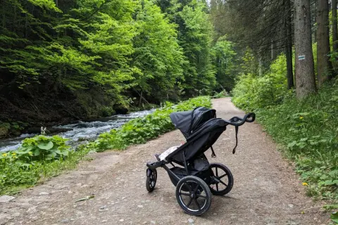 Wózek dziecięcy na leśnej ścieżce. Idealne zakopane szlaki dla dzieci z wózkiem, obok szumiącego potoku.