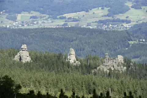 Skaliste formacje, znane jako Pielgrzymy, górują nad lasem w Karkonoszach. W oddali widać zabudowania Karpacza.