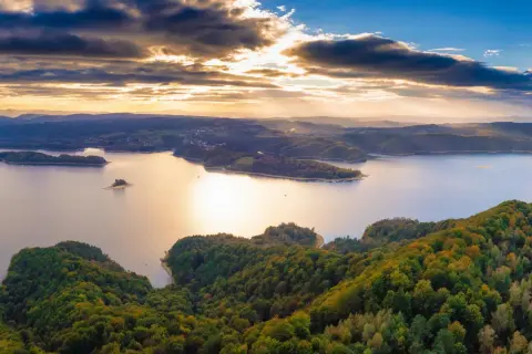 Zachód słońca nad jeziorem Solina. Zalesione wzgórza i łagodne solina szczyty w jesiennych barwach.