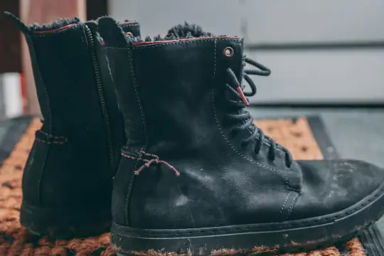 Czarne, znoszone buty zimowe na macie. Szukasz domowych sposobów na śmierdzące buty? Zobacz, jak je odświeżyć!