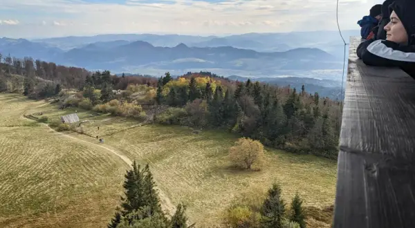 Widok z wieży widokowej na **Lubań szczyt**. Jesienne barwy lasów i pól, w oddali pasmo górskie.