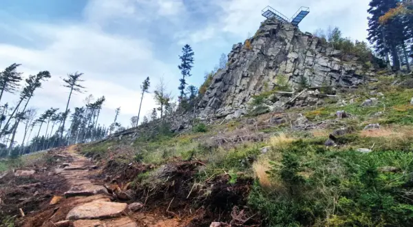Kamienista ścieżka prowadzi ku skalnej grani z platformą widokową. To szlak na Trojak w Lądku-Zdroju, otoczony dziką przyrodą.