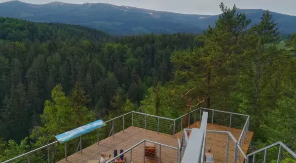 Drewniany punkt widokowy w Karpaczu z widokiem na Karkonosze. Dwie kobiety odpoczywają na tarasie.