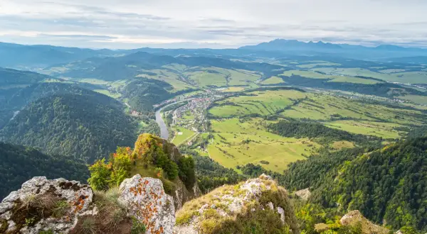 Widok z góry na dolinę z rzeką i miasteczkiem, w oddali majaczą góry. Widok z Trzech Koron.