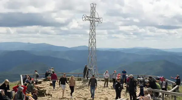 Tłum turystów na szczycie Tarnicy w Bieszczadach, podziwiających rozległą panoramę gór.