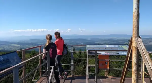 Dwie dziewczyny podziwiają panoramę z wieży widokowej na **kalenicy szczyt**. W tle rozciąga się malowniczy krajobraz Gór Sowich.