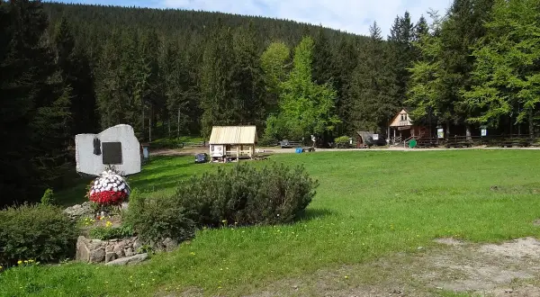 Przełęcz Krowiarki, z pomnikiem i chatkami, otoczona lasem.