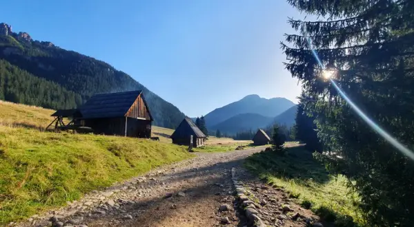Kamienne schroniska pasterskie w dolinie, z widokiem na grześ szczyt. Słoneczny poranek w górach.