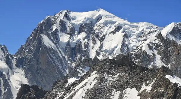 Majestatyczny Mont Blanc, gdzie leży, w Alpach, pokryty śniegiem i lodem, góruje nad skalistymi zboczami.