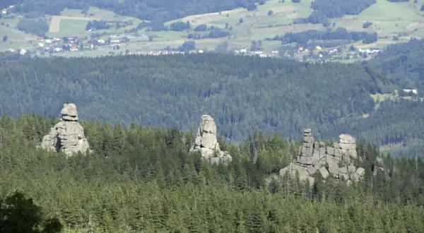 Skaliste formacje, znane jako Pielgrzymy, górują nad lasem w Karkonoszach. W oddali widać zabudowania Karpacza.