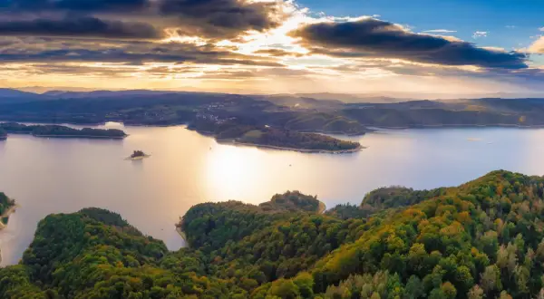 Zachód słońca nad jeziorem Solina. Zalesione wzgórza i łagodne solina szczyty w jesiennych barwach.