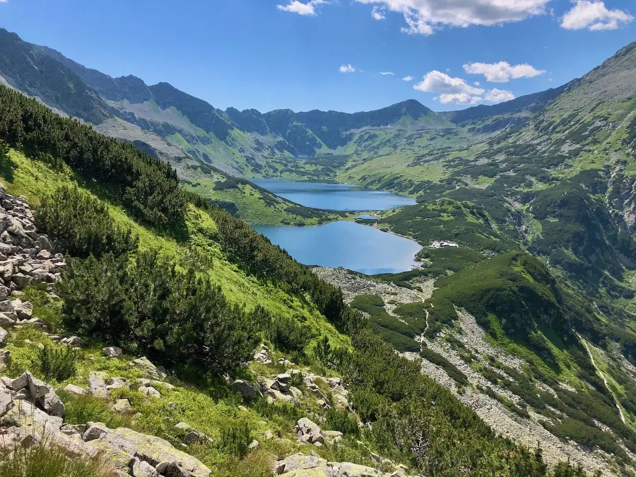 Widok na Morskie Oko i Dolinę Pięciu Stawów w jeden dzień. Błękitne jeziora otoczone zielonymi zboczami Tatr.