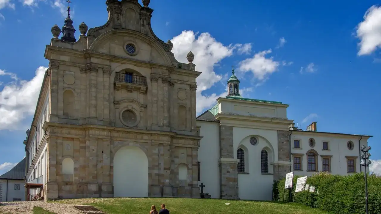 Kamienny klasztor na Łysej Górze, z charakterystyczną wieżyczką i kopułą, na tle błękitnego nieba z chmurami.