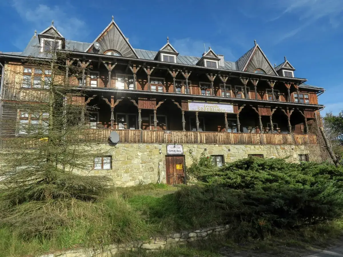 Drewniana willa z werandą, przypominająca architekturą osadę czorsztyn. Na fasadzie widnieje szyld