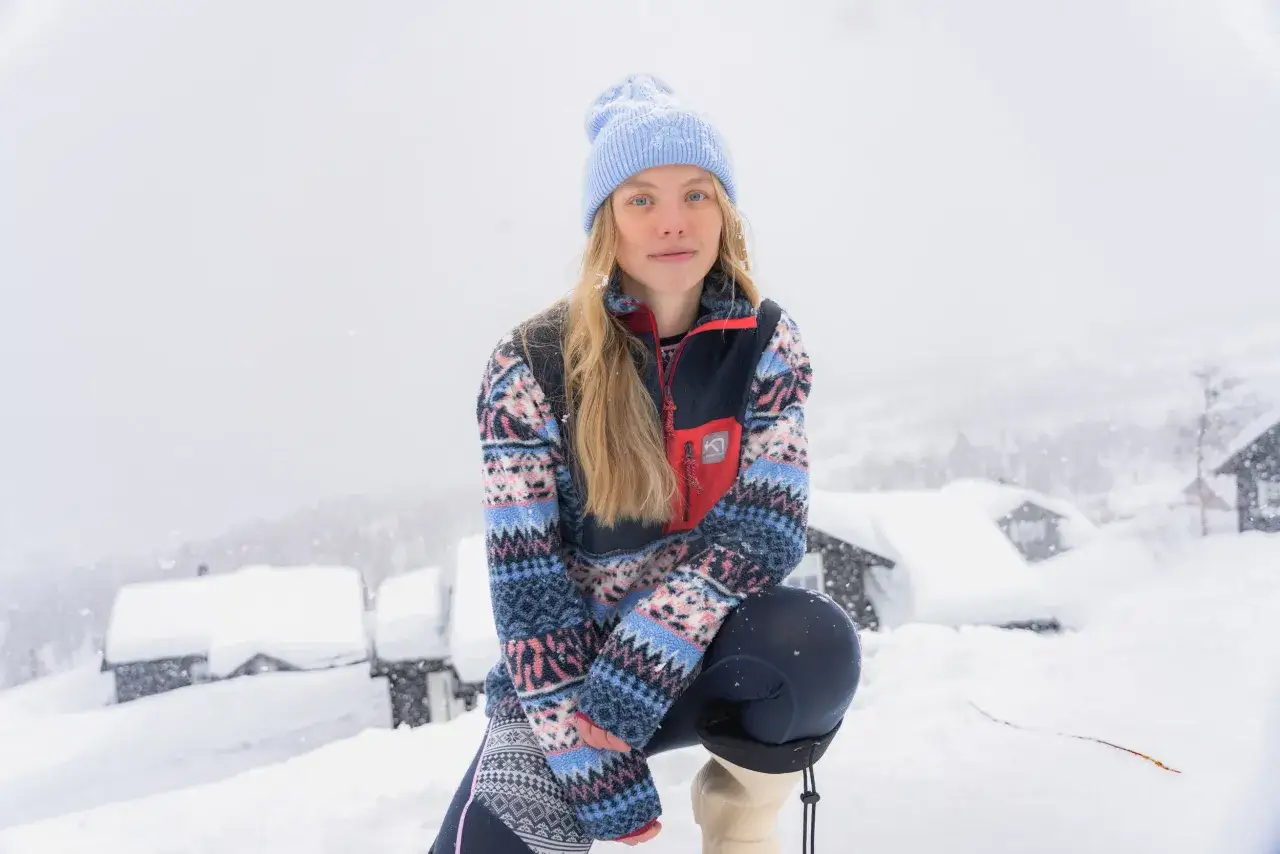 Młoda kobieta w czapce i polarze z norweskimi wzorami, idealna na zimowe przygody. Skandynawskie marki outdoorowe w akcji.