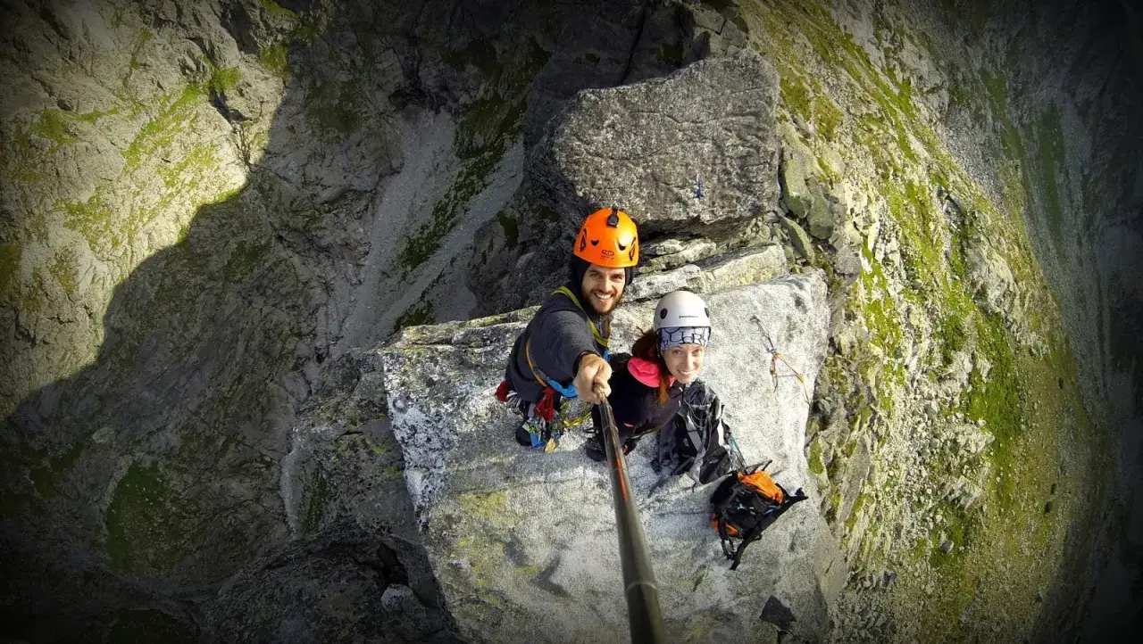 Uśmiechnięci alpiniści na skalnej półce w Tatrach, gotowi na wspinaczkę.