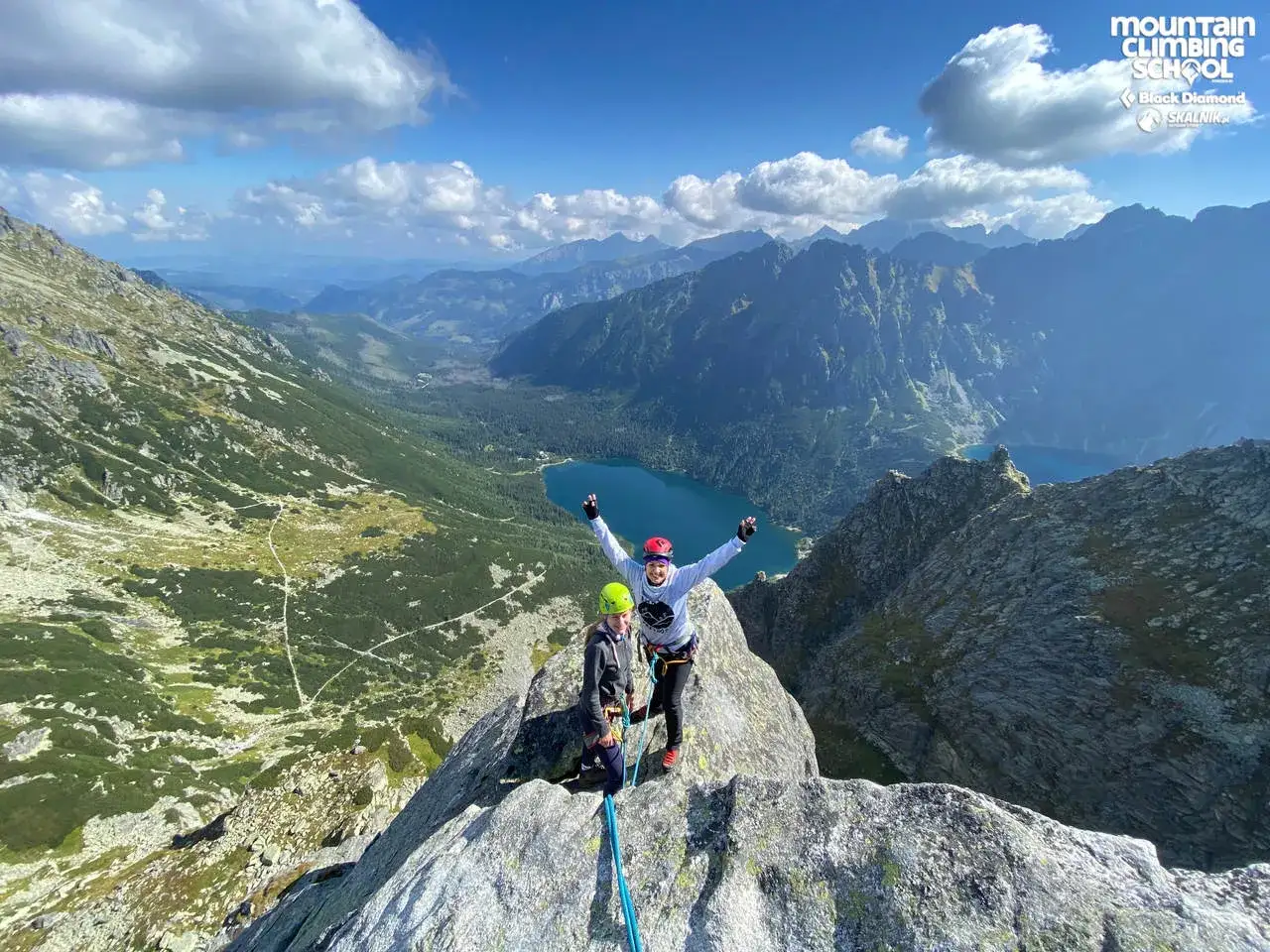 Dw&oacute;ch wspinaczy na szczycie, radość po udanym wejściu na mnicha. W tle malownicze Tatry i Morskie Oko.