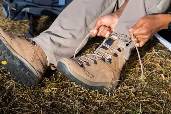 Przygotowanie do wędrówki. Osoba sznuruje brązowe buty trekkingowe z podeszwą Vibram XS Trek, gotowa na przygodę.