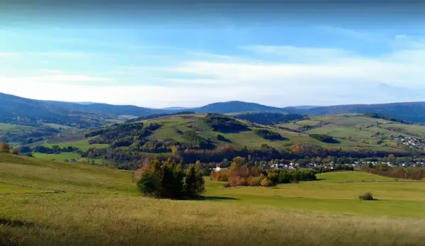 Malowniczy krajobraz z zielonymi wzgórzami i lasami, gdzieś w tle majaczy góra Grzywacka.