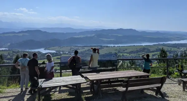 Widok z góry Wdżar na jezioro i góry. Grupa turystów podziwia panoramę.
