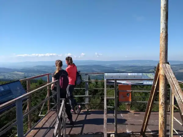 Dwie dziewczyny podziwiają panoramę z wieży widokowej na **kalenicy szczyt**. W tle rozciąga się malowniczy krajobraz Gór Sowich.