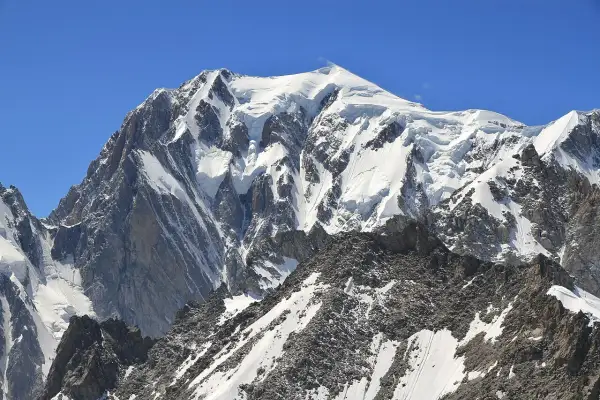 Majestatyczny Mont Blanc, gdzie leży, w Alpach, pokryty śniegiem i lodem, góruje nad skalistymi zboczami.