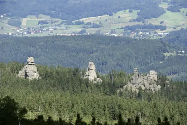 Skaliste formacje, znane jako Pielgrzymy, górują nad lasem w Karkonoszach. W oddali widać zabudowania Karpacza.