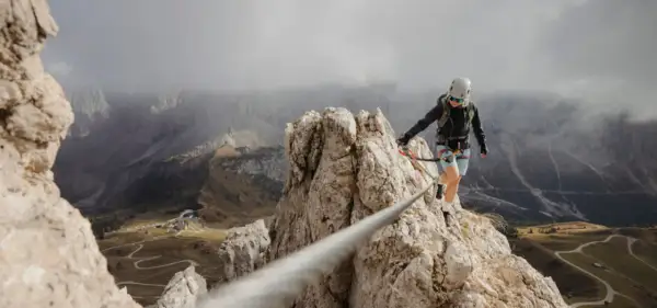 Kobieta na via ferrata, pokonująca skalną grań. Widok zapiera dech w piersiach, a droga jest wyzwaniem.