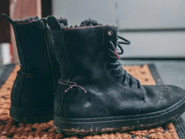 Czarne, znoszone buty zimowe na macie. Szukasz domowych sposobów na śmierdzące buty? Zobacz, jak je odświeżyć!